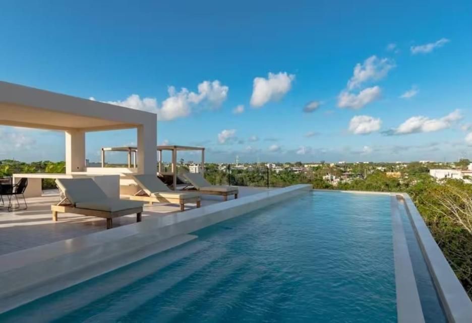 Rooftop infinity pool with lounge beds over the jungle